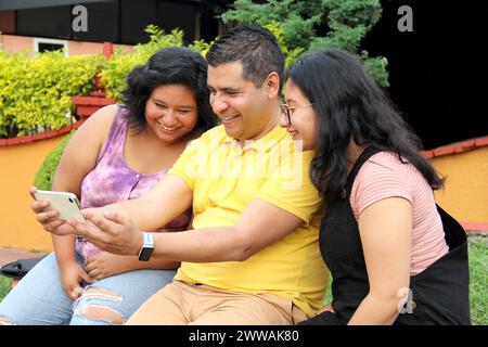 Geschiedener alleinstehender Vater mit seinen dunkelhäutigen Töchtern im Teenageralter aus Latino verbrachte Spaß mit dem Handy, um Selfies zu machen Stockfoto