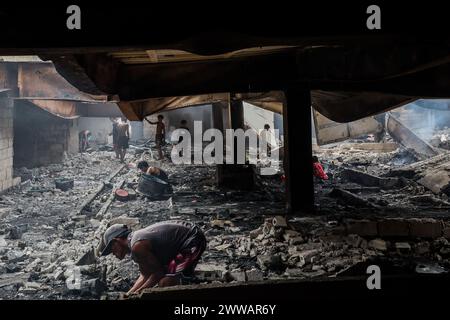 Peking, Philippinen. März 2024. Die Bewohner suchen nach ihrem Besitz aus ihren verkohlten Häusern nach einem Brand in einem Slumgebiet in Manila, den Philippinen, 22. März 2024. Donnerstagnacht brach ein Feuer aus und zerstörte 140 Häuser, laut dem philippinischen Büro für Feuerschutz. Quelle: Rouelle Umali/Xinhua/Alamy Live News Stockfoto