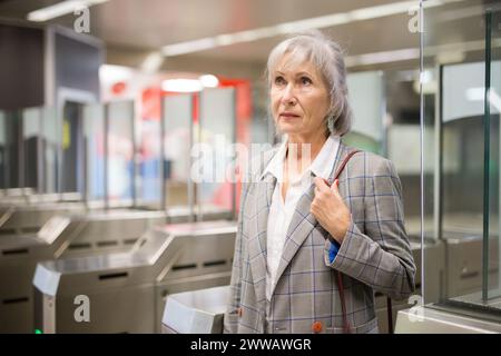 Reife Dame geht durch die Schranken in der U-Bahn-Station Stockfoto