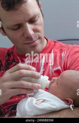 Vater gibt die Flasche seinem Kind auf der Entbindungsstation. Stockfoto