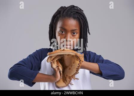 Baseball-, Porträt- und Kinderhandschuhe in einem Studio mit Spiel-, Sport- und Fitnessausrüstung mit Kinderfänger. Jugend und ernster afrikanischer Junge mit Moderne Stockfoto