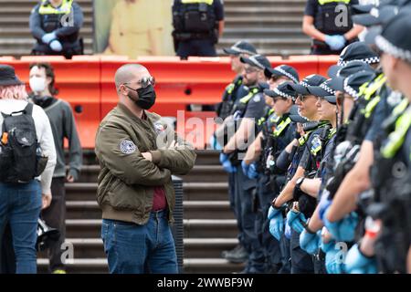 Ein antifaschistischer Demonstrant steht während eines Anti-Trans-Protests und Gegenprotests vor einer Polizeilinie. Die Schritte des viktorianischen Parlaments werden Zeuge einer Kollision von Ideologien, während Anti-Trans-Demonstranten eine Plattform fordern, während linke Aktivisten vehement Widerstand leisten. Die Emotionen steigen in der aufgeladenen Atmosphäre auf, und die Polizeipräsenz wird verstärkt, um die Ordnung aufrechtzuerhalten. Die Polizei versuchte, Ordnung und Frieden aufrechtzuerhalten. Es wurden Schläge geworfen und ein Pressefotograf wurde von der Polizei bei den Zusammenstößen zu Boden geschlagen. Stockfoto