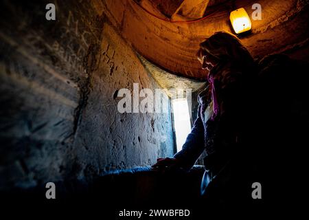 Mitarbeiter und Freiwillige der Kathedrale von Gloucester machen letzte Prüfungen und Vorbereitungen in einer mittelalterlichen Treppe und bewundern einige alte Graffiti aus Stein hoch oben im Turm der Kathedrale, wo sie für die Saison 2024 der Öffentlichkeit geöffnet wird. Bilddatum: Freitag, 22. März 2024. Stockfoto