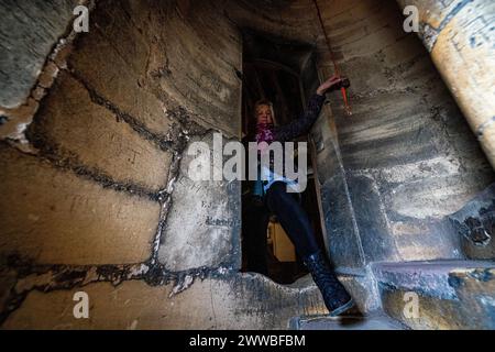 Mitarbeiter und Freiwillige der Kathedrale von Gloucester führen letzte Prüfungen und Vorbereitungen in einer mittelalterlichen Treppe mit Graffiti aus Stein aus dem 16. Jahrhundert hoch oben im Dom durch, wo sie für die Saison 2024 der Öffentlichkeit geöffnet wird. Bilddatum: Freitag, 22. März 2024. Stockfoto