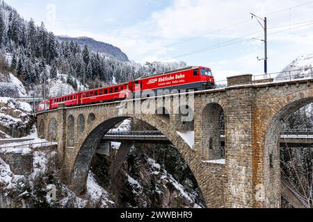 Solis, Schweiz - 10. Januar 2024: Personenzug der Rhätischen Bahn am Soliserviadukt auf der Albulalinie in den Schweizer Alpen in Solis, Schweiz. Stockfoto