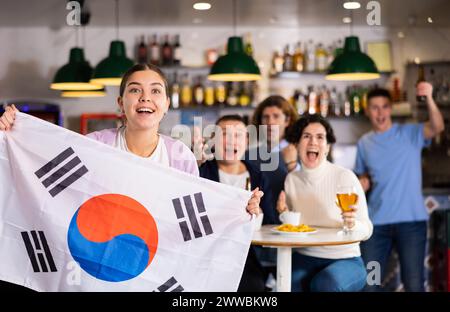 Eine Gruppe von glücklichen Freunden mit der Flagge von Südkorea, die den Sieg ihrer Lieblingsmannschaft in der Bierstube feiern Stockfoto