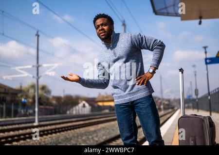 Ein wütender Mann mit einem Koffer, der auf einem Bahnhof steht. Stockfoto