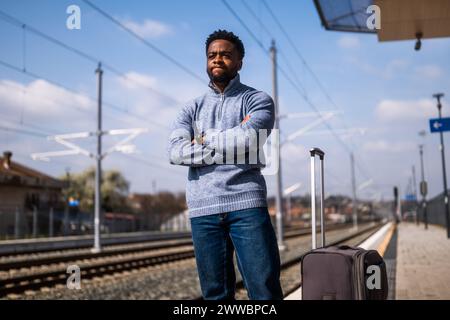 Ein wütender Mann mit einem Koffer, der auf einem Bahnhof steht Stockfoto