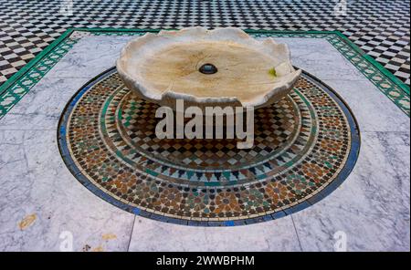 Der komplizierte Mosaikboden mit einem Springbrunnen im Herzen der ältesten islamischen Schule in Marokko. Stockfoto