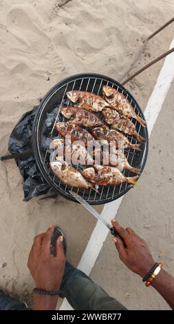 Fisch über Holzkohle am Sandstrand grillen. Stockfoto