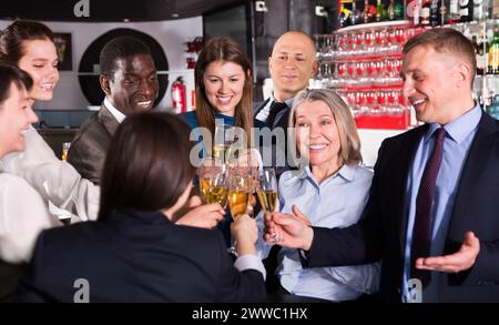 Kollegen klirren auf der Firmenfeier mit einem Glas Champagner Stockfoto
