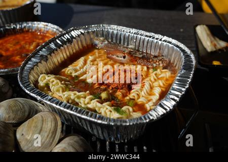 Instant-Ramen gekocht in einem Einwegbehälter aus Aluminium mit Meeresfrüchten wie Krabben Stockfoto