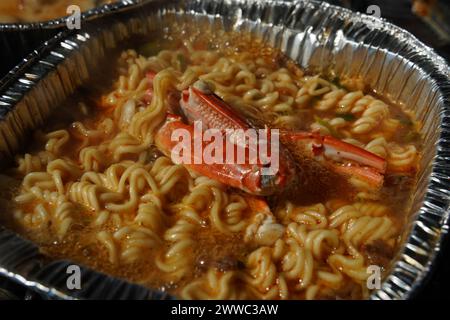 Instant-Ramen gekocht in einem Einwegbehälter aus Aluminium mit Meeresfrüchten wie Krabben Stockfoto