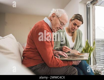 Häuslicher Betreuer mit Mann, der sich das Fotoalbum anschaut Stockfoto