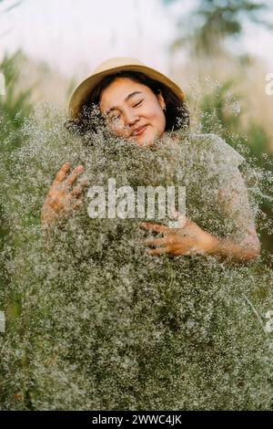 Sorglose reife Frau, die einen Haufen gypsophila-Blumen umschließt Stockfoto