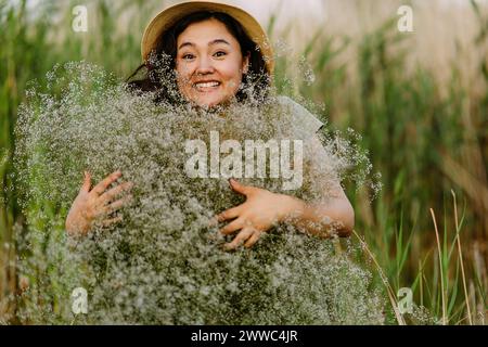 Fröhliche reife Frau mit einem Haufen gypsophila-Blumen auf dem Feld Stockfoto