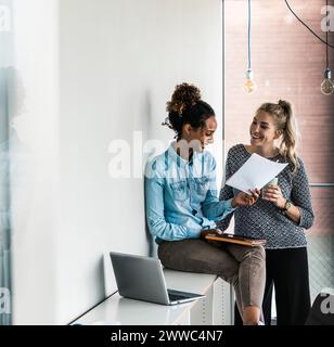 Glückliche Geschäftskollegen, die im Büro über Dokumente diskutieren Stockfoto