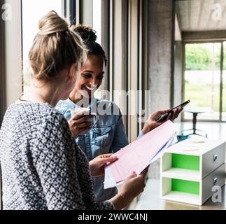 Glückliche Geschäftskollegen, die im Büro über Dokumente diskutieren Stockfoto