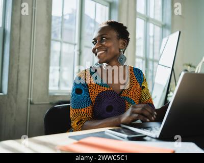 Lächelnd Geschäftsfrau mit Laptop am Schreibtisch im Büro Stockfoto