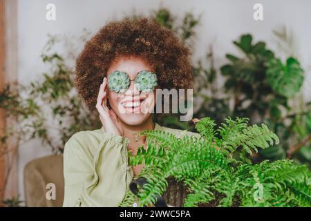 Lächelnde Frau mit echeveria-Brille in der Nähe der Pflanze zu Hause Stockfoto