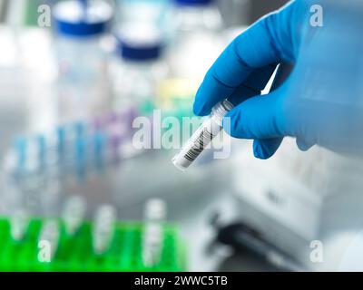 Hand eines Reifen Wissenschaftlers, der DNA-Probe in einem Fläschchen im Labor hält Stockfoto