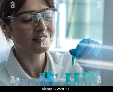 Lächelnder Wissenschaftler, der DNA-Probe im Labor in eppendorf-Röhrchen platziert Stockfoto