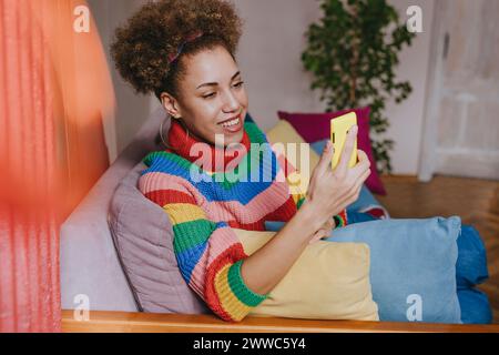 Lächelnde Frau mit Smartphone auf dem Sofa Stockfoto