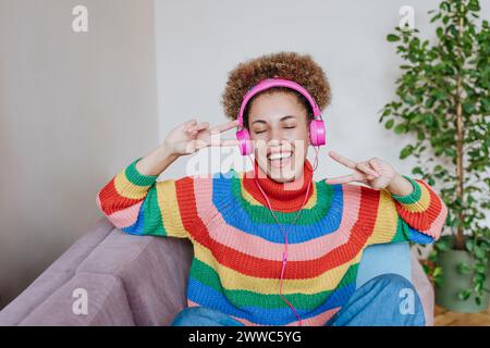 Glückliche Frau, die Musik hört und Friedenszeichen zeigt Stockfoto