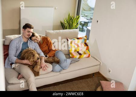 Liebevolles Paar, das mit Hund auf dem Sofa sitzt Stockfoto