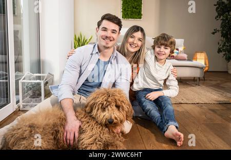 Glückliche Familie, die zu Hause mit Hund im Wohnzimmer sitzt Stockfoto