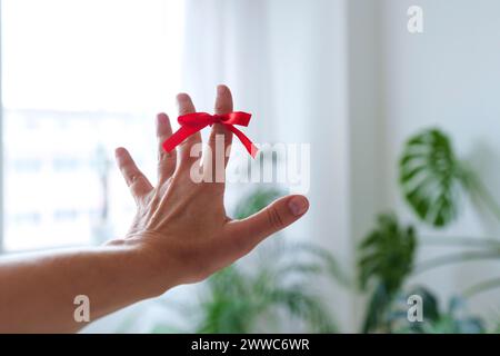 Hand einer Frau mit Erinnerungsknoten am Zeigefinger zu Hause Stockfoto