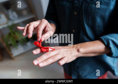 Frau, die zu Hause das Band des Erinnerungsknotens am Finger anpasst Stockfoto