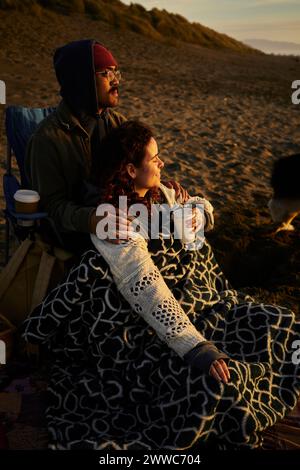 Junges Paar, das sich am Strand bei Sonnenuntergang entspannt Stockfoto