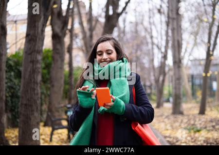 Glückliche Frau, die ihr Smartphone im Park benutzt Stockfoto