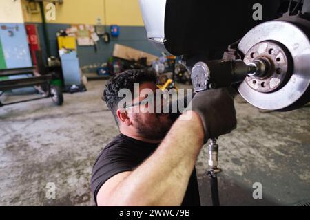 Mechanischer Demontage des Fahrzeugteils mit Schlagschrauber in der Werkstatt Stockfoto