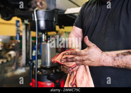 Mechaniker, der die Hände mit einem Tuch in der Werkstatt reinigt Stockfoto