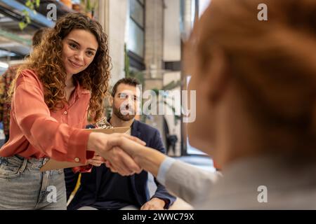 Ein lächelnder Rekrutierer, der mit dem Kandidaten im Amt die Hand schüttelt Stockfoto