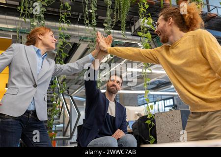 Glückliche Geschäftskollegen geben High-Five im Büro Stockfoto