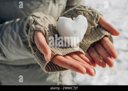 Frau, die einen herzförmigen Schneeball in der Hand hält Stockfoto