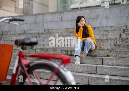 Traurige junge Frau, die auf Stufen sitzt Stockfoto
