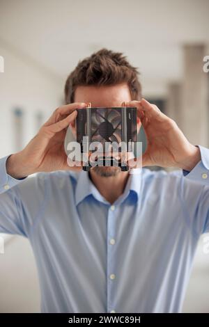 Techniker, der das Gesicht mit dem CPU-Lüfter in der Werkstatt bedeckt Stockfoto