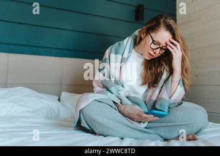 Enttäuschte Frau, die zu Hause ihr Smartphone im Schlafzimmer benutzte Stockfoto
