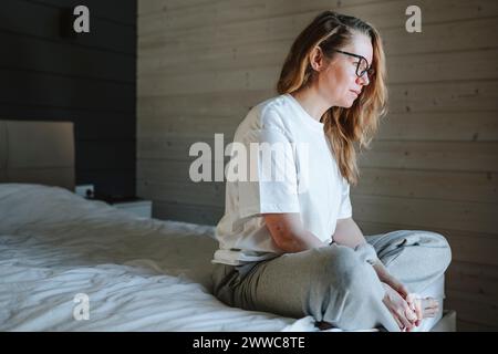 Einsame Frau, die zu Hause auf dem Bett sitzt Stockfoto