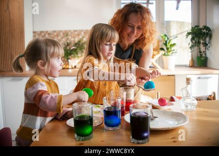 Mutter und Töchter färben Ostereier zu Hause Stockfoto