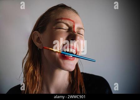 Frau mit Pinsel im Mund vor grauem Hintergrund Stockfoto