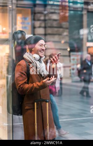 Glücklicher Mann, der eine Gitarrenhülle trägt und über das Smartphone spricht Stockfoto