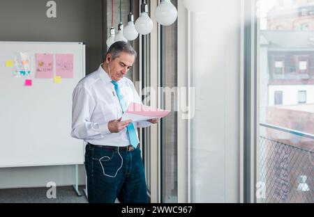 Leitender Geschäftsmann, der das Dokument am Arbeitsplatz prüft Stockfoto