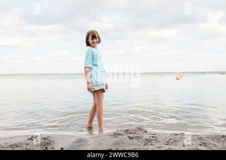 Glückliches Mädchen, das am Ufer am See steht Stockfoto