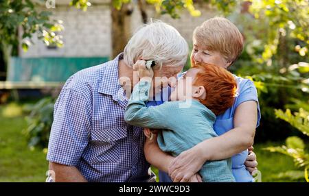 Fröhlicher Junge, der mit Großeltern im Garten spielt Stockfoto