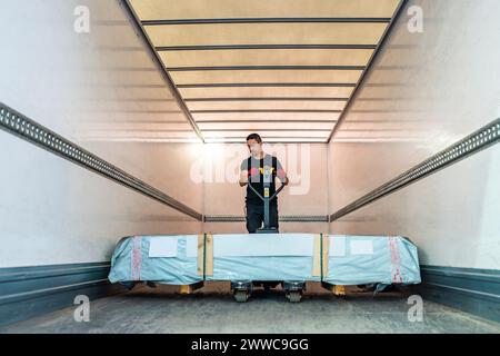 Arbeiter schiebt Palettenhubwagen in Frachtcontainer Stockfoto